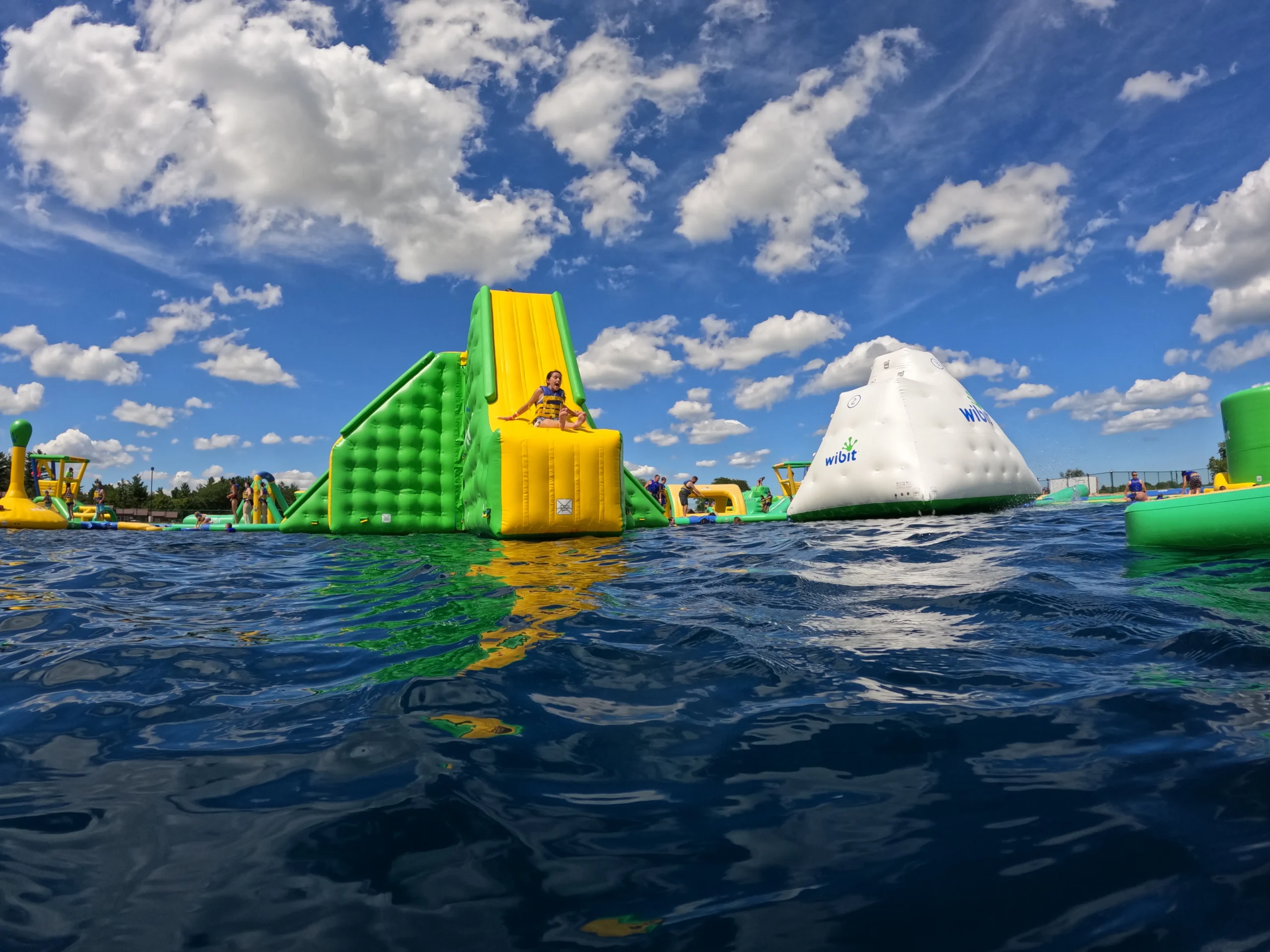 child slides down inflatable slide in water